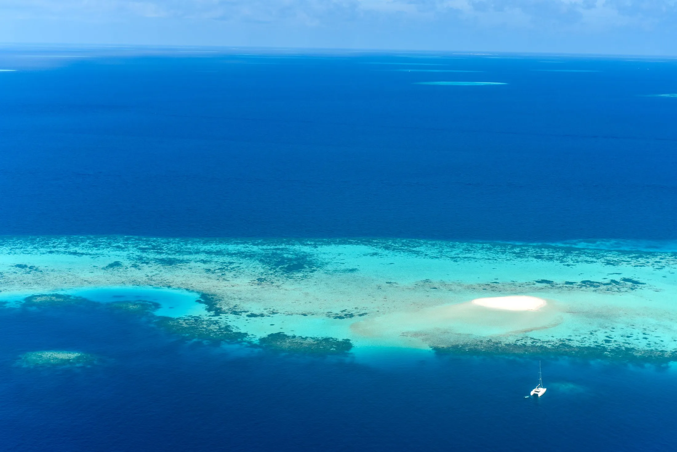 Aerial view of a tropical reef, sandbar and deep blue water